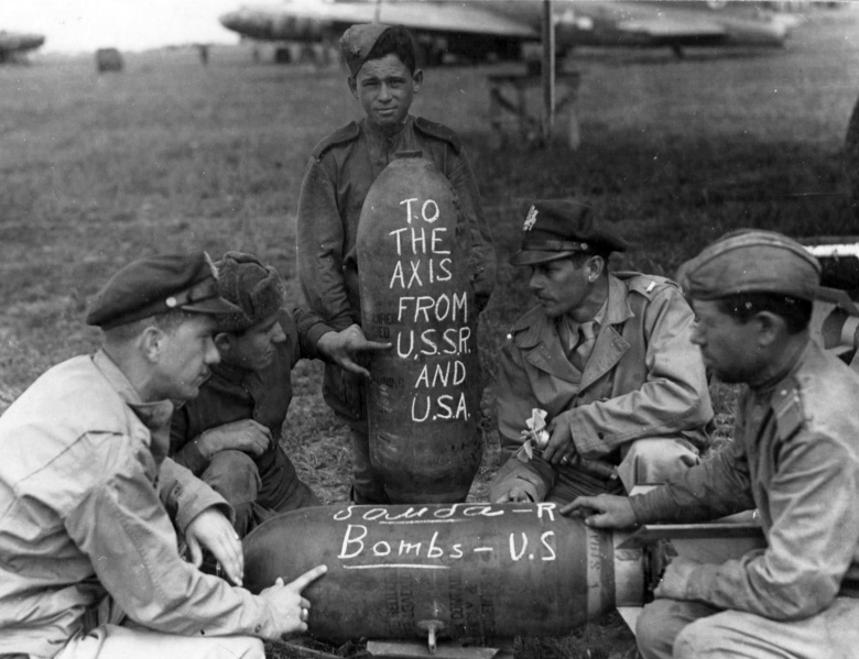 Советские и американские военнослужащие пишут послания врагу на авиабомбах. На заднем плане бомбардировщик B-17 «Летающая крепость» и транспортный самолет C-47 «Дакота». Полтава, лето 1944 г.
