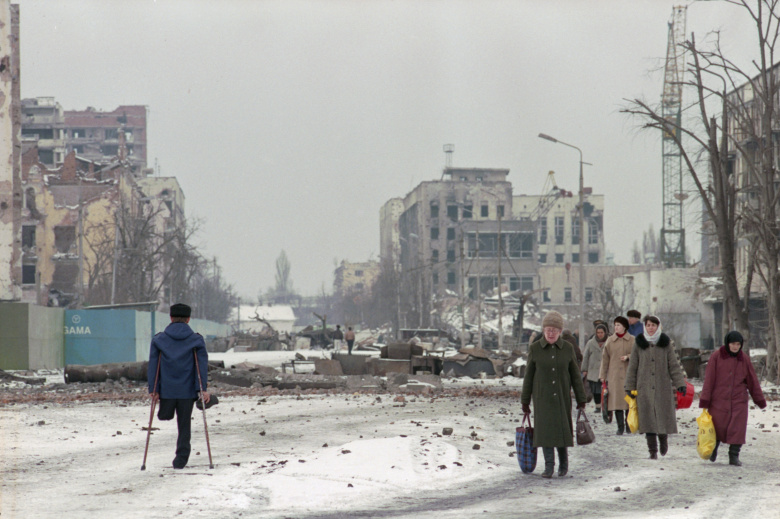 Жители Грозного идут среди разрушенных баррикад возле бывшего Президентского дворца, 13 февраля 1996 года