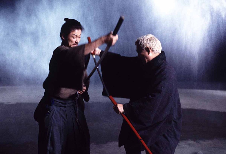 Такэси Китано (справа) и Таданобу Асано в фильме «Затойчи» (2003). Заглавный герой (его играет Китано) — слепой самурай, который благодаря необычайной остроте своих чувств способен победить в поединке любого противника.