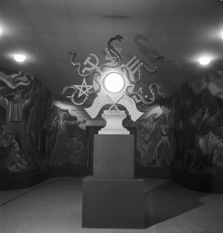 Инсталляция на выставке «Советский рай» (Das Sowjet Paradies), прошедшей в Праге весной 1942 г., указывает на (снизу слева по часовой стрелке) Коминтерн, большевизм, мировое еврейство, II Интернационал и мировое масонство  как основы англо-американской «плутодемократии».