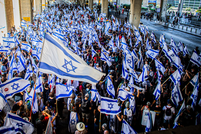 Протестующие размахивают израильскими флагами во время демонстрации в международном аэропорту Бен-Гурион, Иерусалим, Израиль, 11 июля 2023 года