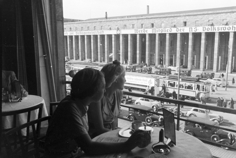 Две молодые женщины наблюдают за оживленным движением перед главным вокзалом в Штутгарте, Германия, 1930-е годы.