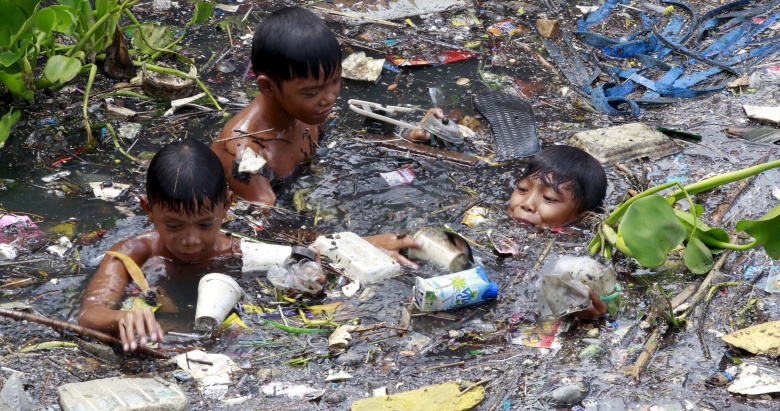 Дети собирают мусор в загрязненной реке. Филиппины.