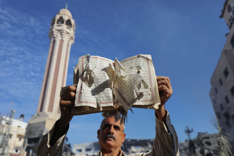 Палестинец показывает повреждённый Коран после авиаудара Израиля по мечети и больнице Яффо в Дайр-эль-Балахе, 8 декабря 2023 года