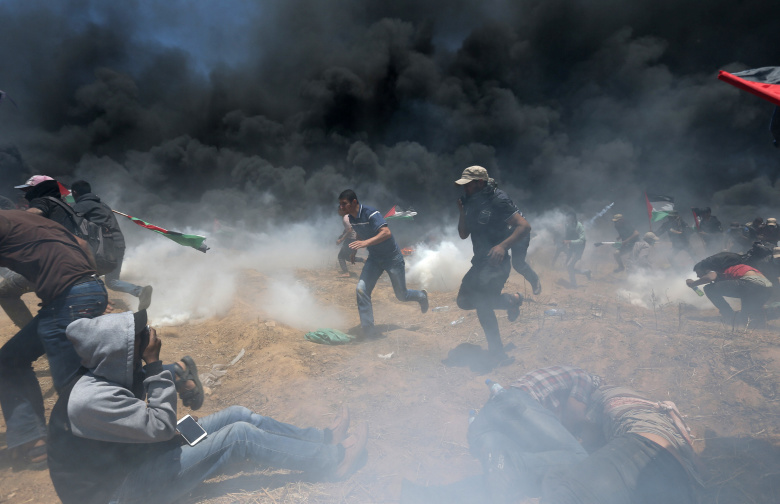 Палестинцы скрываются от слезоточивого газа на границе Израиля и сектора Газа. Фото: Ibraheem Abu Mustafa / Reuters