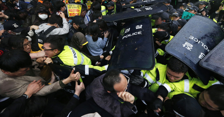 Южнокорейские демонстранты дерутся с полицией, во время марша к президентской резиденции в день памяти жертв затонувшего парома «Севоль».