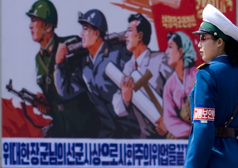 Регулировщица на фоне пропагандистского плаката в Пхеньяне.