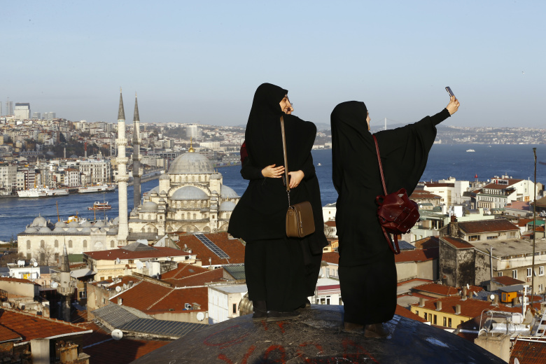 Девушки фотографируются на фоне Новой мечети в Стамбуле.