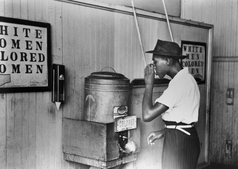 Житель города Оклахома-Сити пьет в отдельном питьевом фонтанчике с надписью «Для цветных», 1939. Фото: Russell Lee / Getty Images
