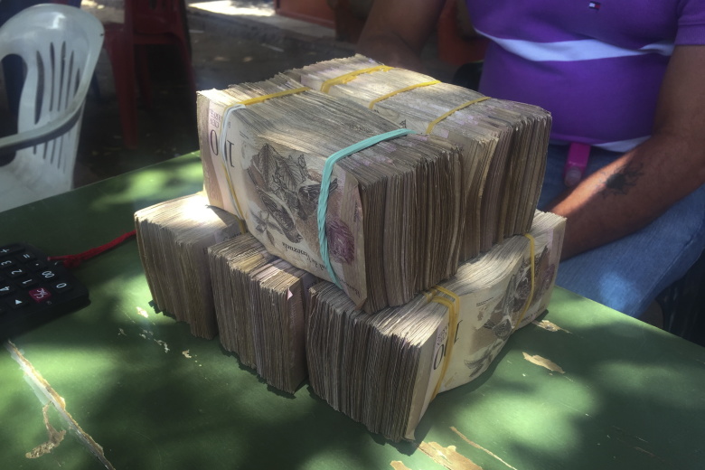 Деньги на столе у продавца, Венесуэла. Фото: Girish Gupta / Reuters