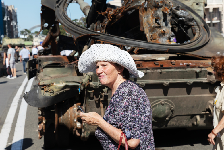 Женщина в Киеве, возле поврежденной российской военной техники
