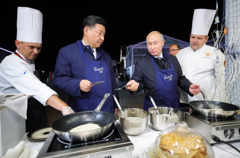 Владимир Путин и Си Цзиньпин готовят блины во время посещения выставки «Улица Дальнего Востока» в рамках Восточного экономического форума во Владивостоке, 11 сентября 2018 года.