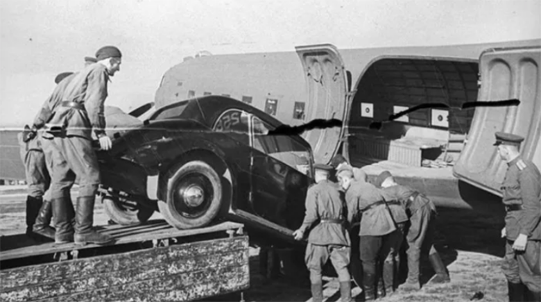 Красноармейцы грузят в самолет «трофейный» легковой автомобиль. Германия, 1945