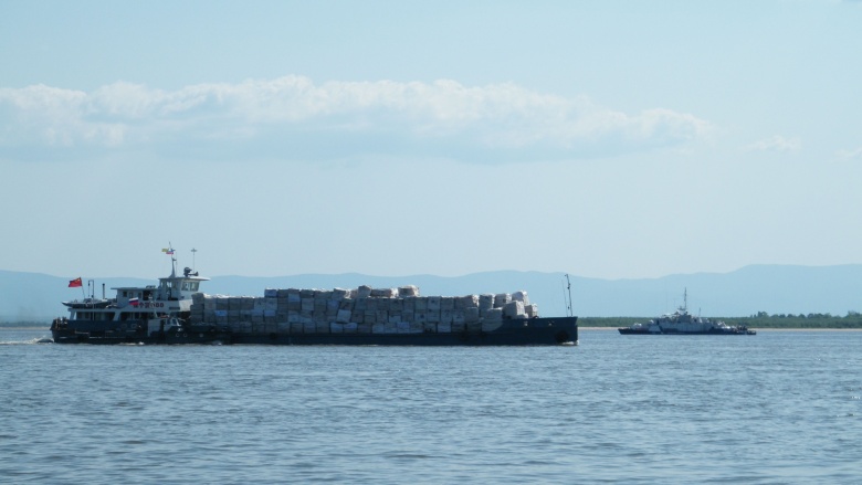 Китайское грузовое судно на Амуре у Хабаровска. На дальнем плане — российский сторожевой корабль Амурской пограничной флотилии.