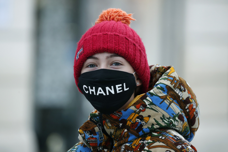 Девушка в маске Chanel. Производство масок было запущено в связи с коронавирусом. Фото: Francois Mori / AP / TASS