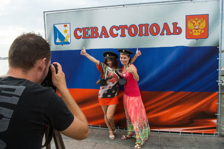 Девушки фотографируются на фоне российского флага в Севастополе.