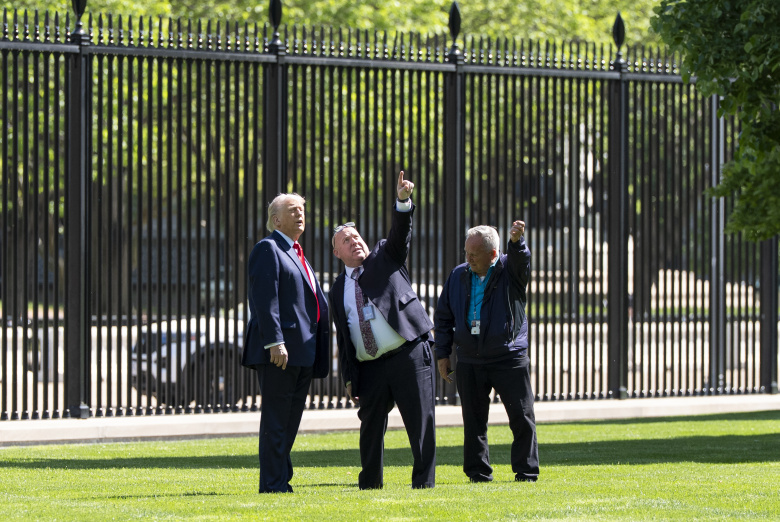 Президент Дональд Трамп (слева) беседует с Дейлом Хейни, главным садовником Белого дома (справа), и другими о новом флагштоке на Северной лужайке Белого дома в среду, 23 апреля 2025 года.