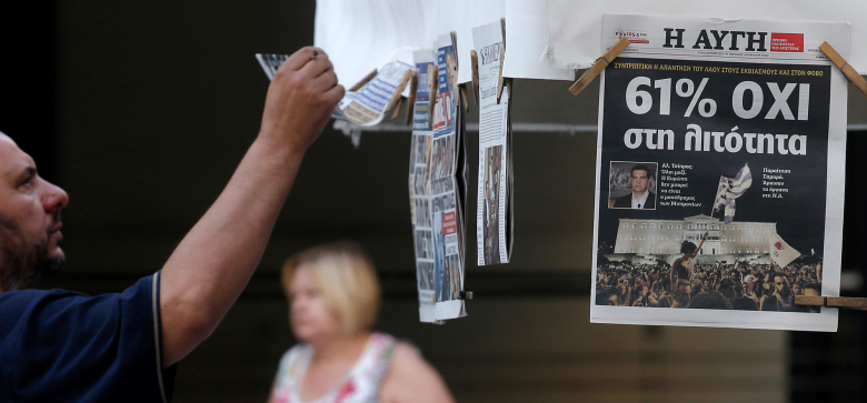 Мужчина изучает газеты, отражающие результаты вчерашнего референдума в Греции.