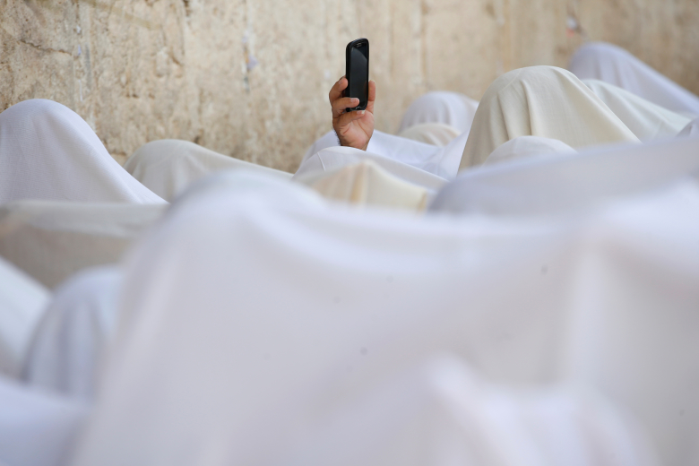Паломница использует мобильный телефон у Стены Плача, Иерусалим. Фото: Baz Ratner / Reuters