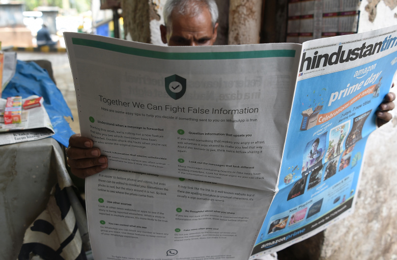 Житель Нью-Дели читает газету с материалом, призывающим бороться с ложными новостями в WhatsApp Фото: Prakash SINGH / AFP