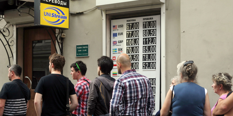 Жители Санкт-Петербурга стоят в очереди у пункта обмена валюты.