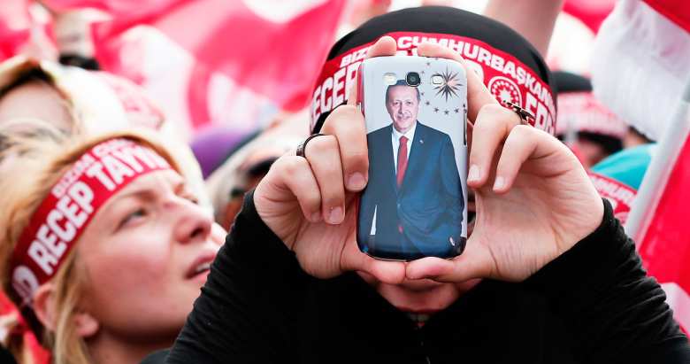 Cторонник партии ПСР держит телефон с изображением президента Турции Реджепом Тайипом Эрдоганом.