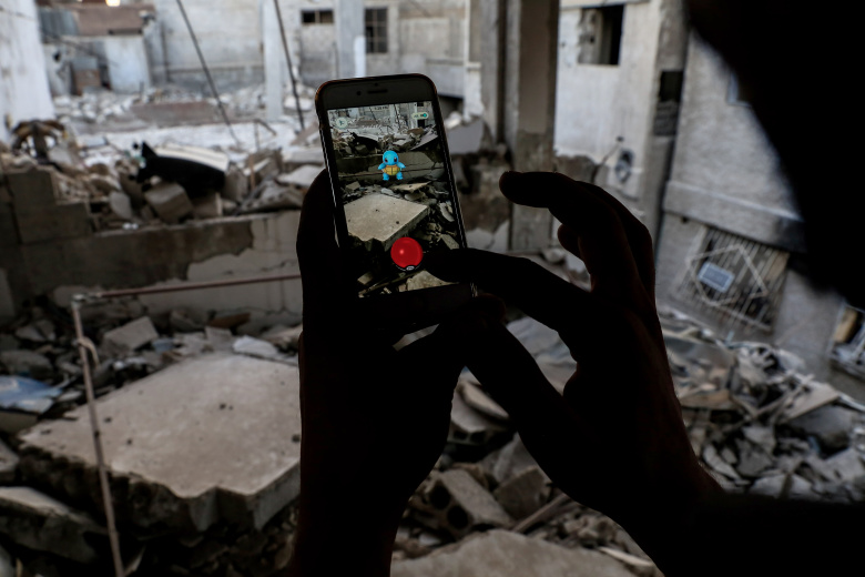 Сириец играет в Pokemon Go на обломках города. Фото: Sameer Al-Doumy / AFP
