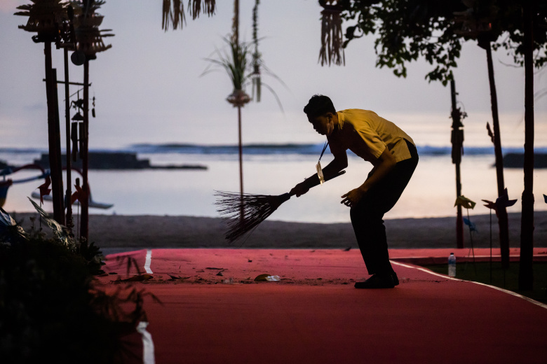 Работник отеля подметает красную ковровую дорожку на пляже на саммите G20 в Нуса-Дуа, Индонезия, ранним утром 15 ноября 2022 года