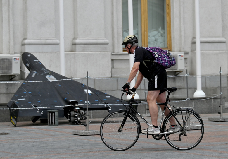 Мужчина проезжает на велосипеде мимо беспилотного летательного аппарата «Шахед 136» («Герань-2»), выставленного у здания Министерства иностранных дел Украины