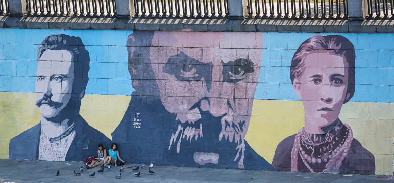 Жители Киева отдыхают у стены, украшенной портретами украинских поэтов Ивана Франко, Тараса Шевченко и Леси Украинки, символов возрождения украинской нации.
