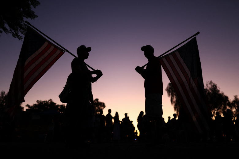 Люди с флагами около мемориала политическому активисту Чарли Кирку у штаб-квартиры Turning Point USA в городе Финикс, штат Аризона, 14 сентября 2025 года