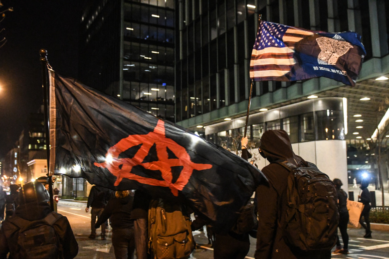 Члены движения «Антифа» идут с флагами «Анархии» и BLM на акции протеста в Вашингтоне, 12 декабря 2020 года