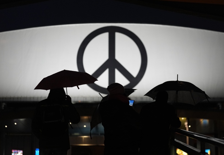 Прохожие идут с зонтиками под проливным дождем. На заднем плане виден большой пацифик, знак мира