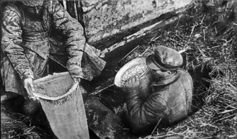 Работники ОГПУ извлекают из ямы спрятанное зерно. Украина, конец 1932 г.