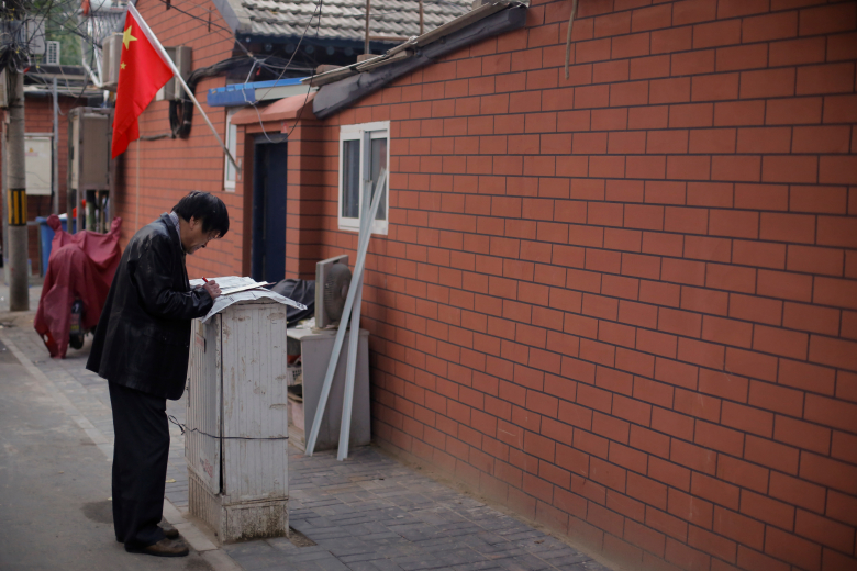 Мужчина читает газету на улице Пекина. Фото: Thomas Peter / Reuters