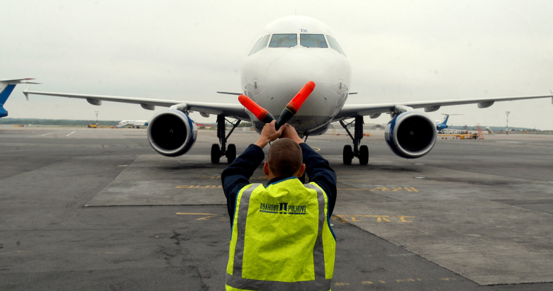 Служащий аэропорта контролирует движение самолета. Фото: Владимир Бертов / Интерпресс / ТАСС