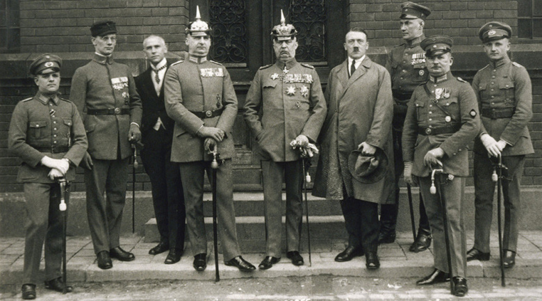 Адольф Гитлер (четвертый справа) у здания суда в день рассмотрения дела о «пивном путче» 1923 г. Рядом с ним (в каске) — генерал Эрих фон Людендорф.