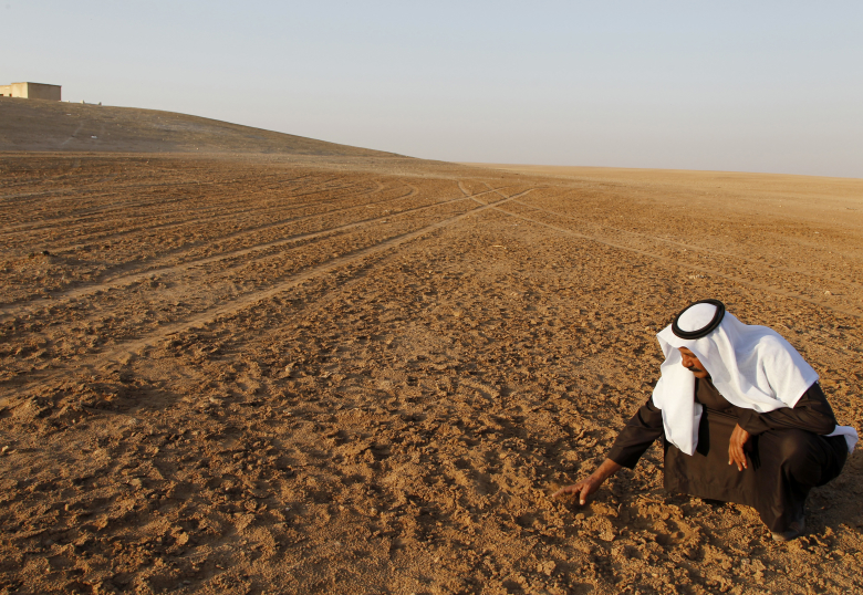Шейх Гази Рашад Хримис трогает высохшую землю в провинции Ракка,  2010год.