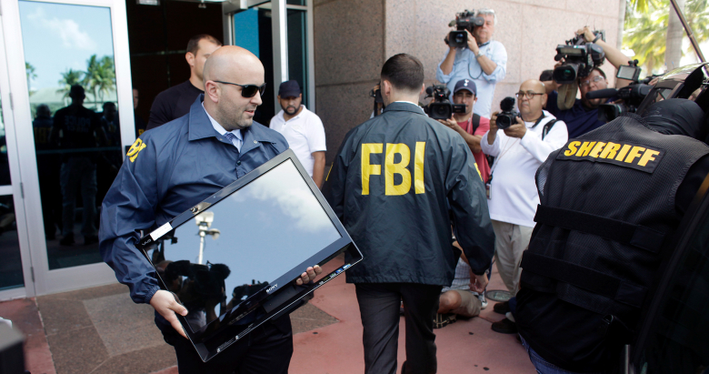 Агенты ФБР США выносят коробки из здания КОНКАКАФ.
