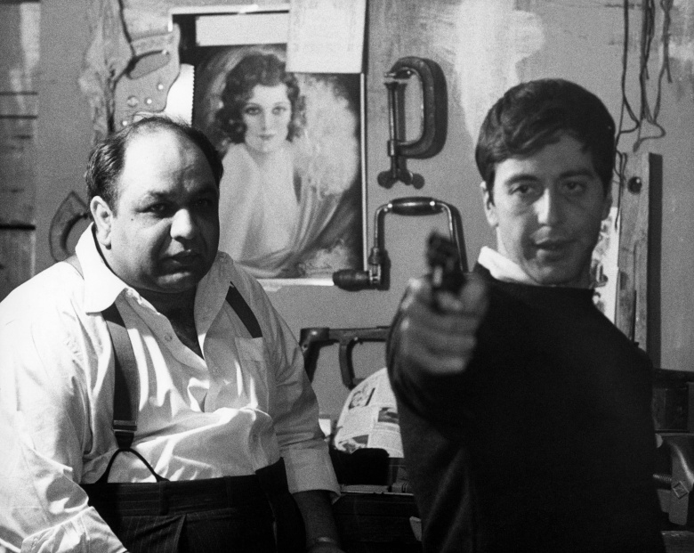 Капореджиме Пит Клеменца (Ричард Кастеллано) учит Майкла Корлеоне (Аль Пачино) обращаться с пистолетом. Кадр из фильма Фрэнсиса Форда Копполы по роману Марио Пьюзо «Крестный отец» (1972)