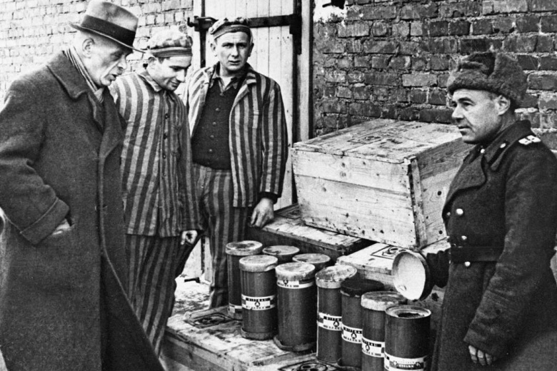 Советский офицер и бывшие узники концлагеря Освенцим возле ящиков с контейнерами отравляющего газа «Циклон-Б»