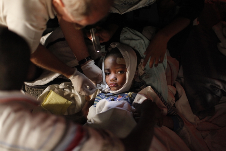 Раненая девочка после землетрясения на Гаити в окружении врачей, 2010 год