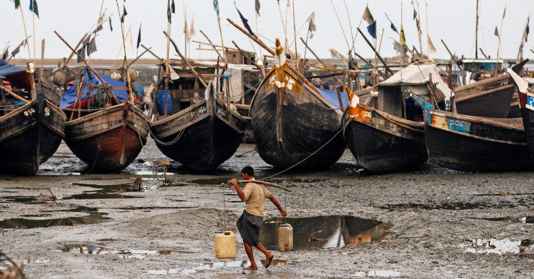Мусульманин рохинджа несет контейнер с водой вблизи пристани в лагере беженцев в пригороде Ситтве, Мьянма.