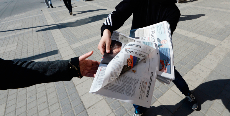 Подросток раздает прохожим свежий номер «Российской газеты» в Симферополе.