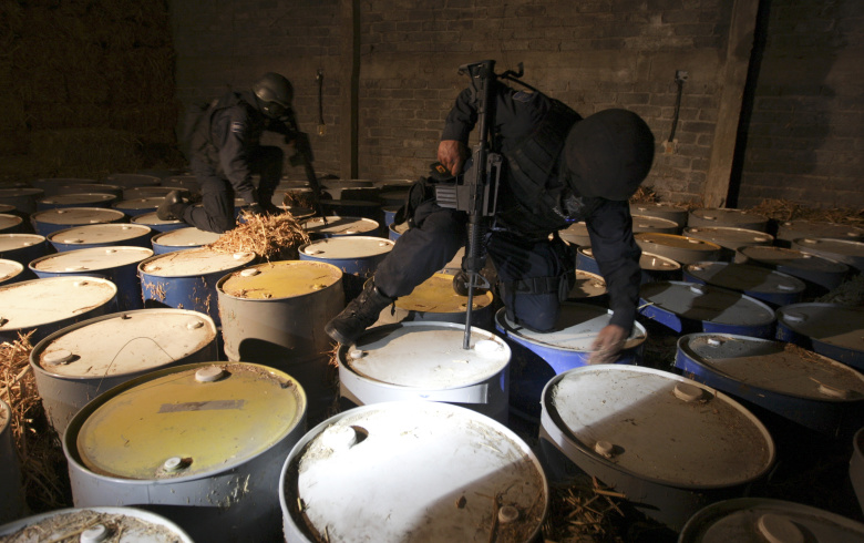 Полицейские обыскивают место, где предположительно хранятся ингредиенты для приготовления метамфетамина, во время операции по поиску членов «Мичоаканской Семьи»