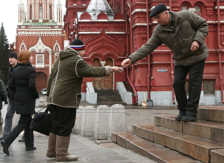 Мужчина подает милостыню у Казанского собора на Красной площади.