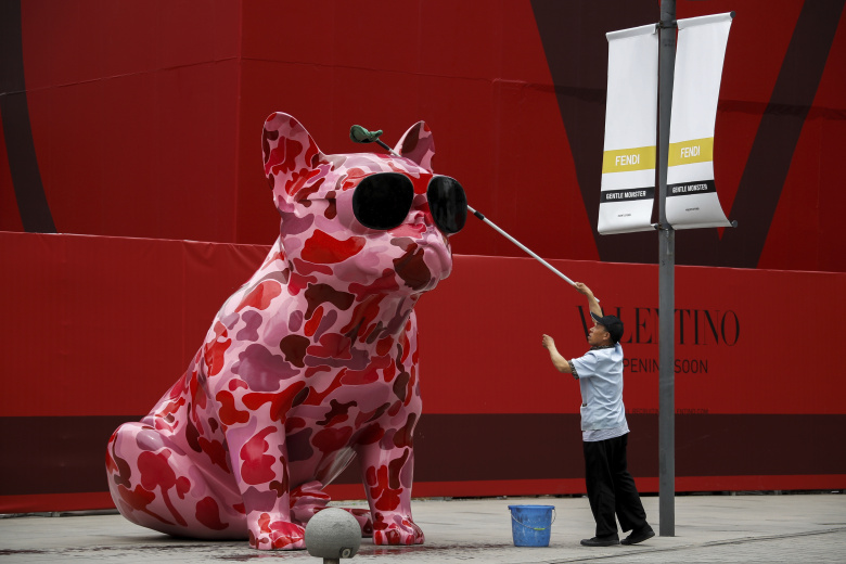 Рабочий вытирает скульптуру собаки возле строящегося бутика модной одежды в популярном торговом центре Пекина.