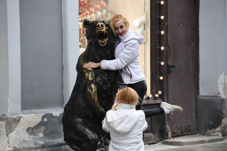 Женщина фотографируется с бронзовой скульптурой медведя в Москве