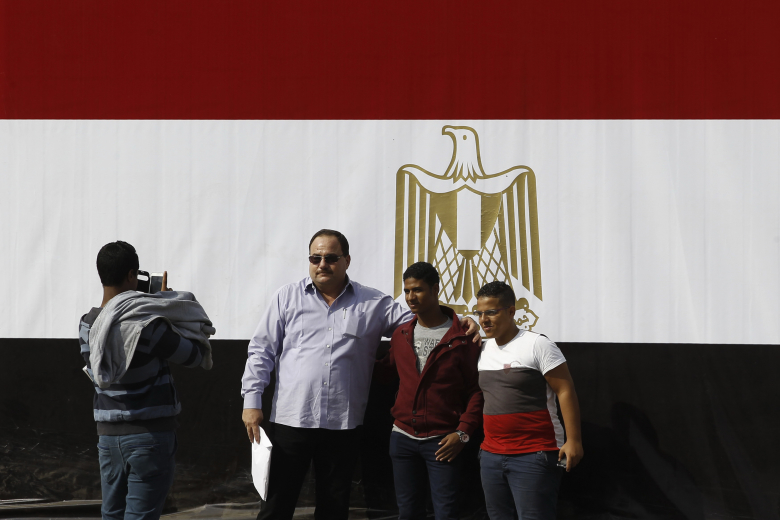 Люди фотографируются напротив мемориала в память о погибших революционерах на площади Тахрир, Каир.