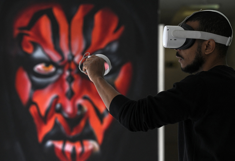 Мужчина использует гарнитуру виртуальной реальности (VR) перед граффити с изображением Дарта Мола, персонажа саги «Звездные войны»